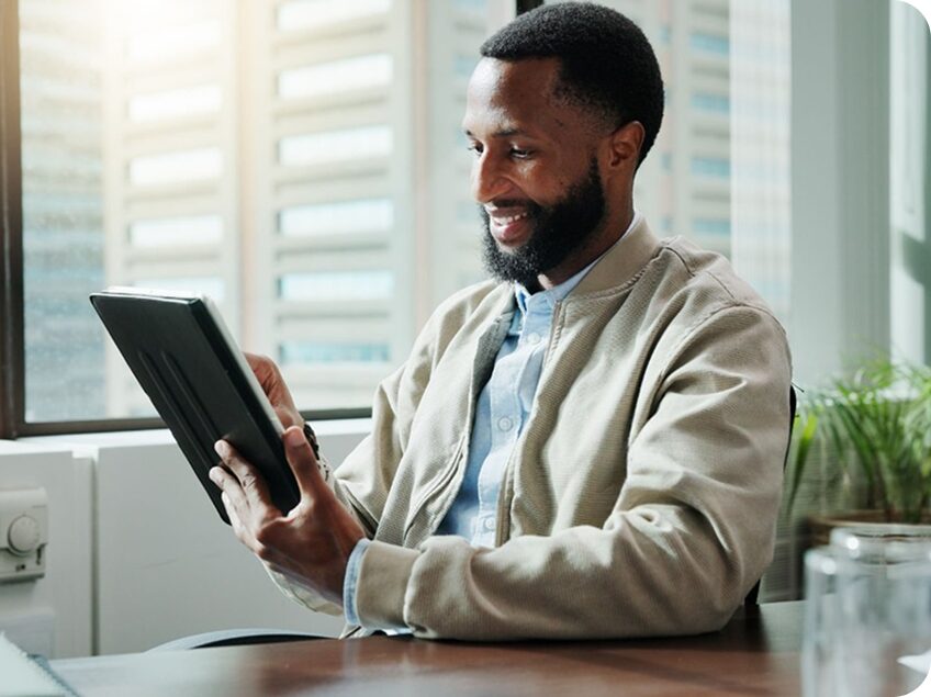 A professional smiling while reading on a tablet